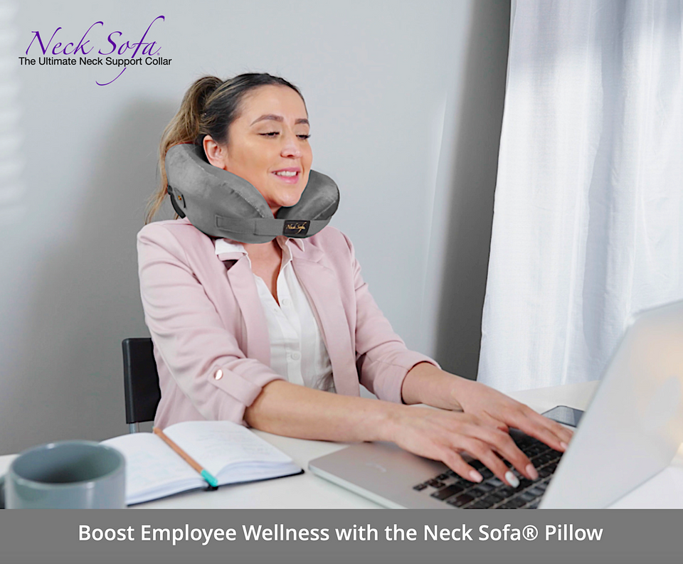 A woman at the office wearing a Grey Neck Sofa Pillow working on the computer related.